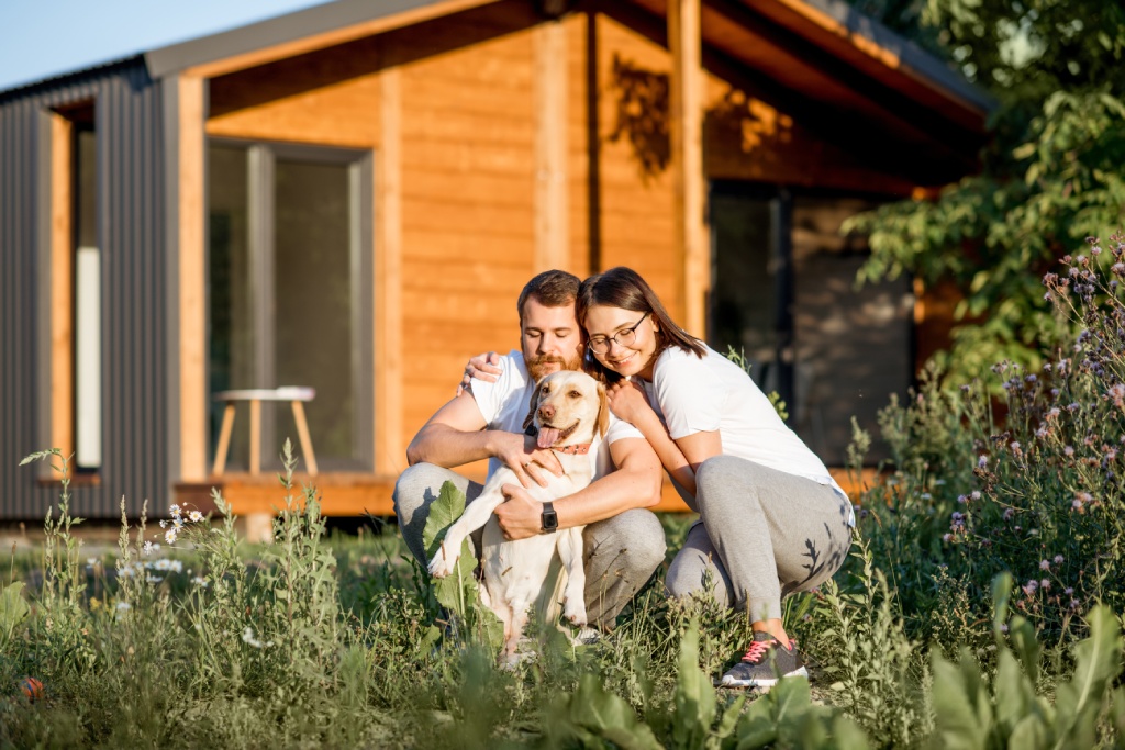 Happy couple and dog in front of home