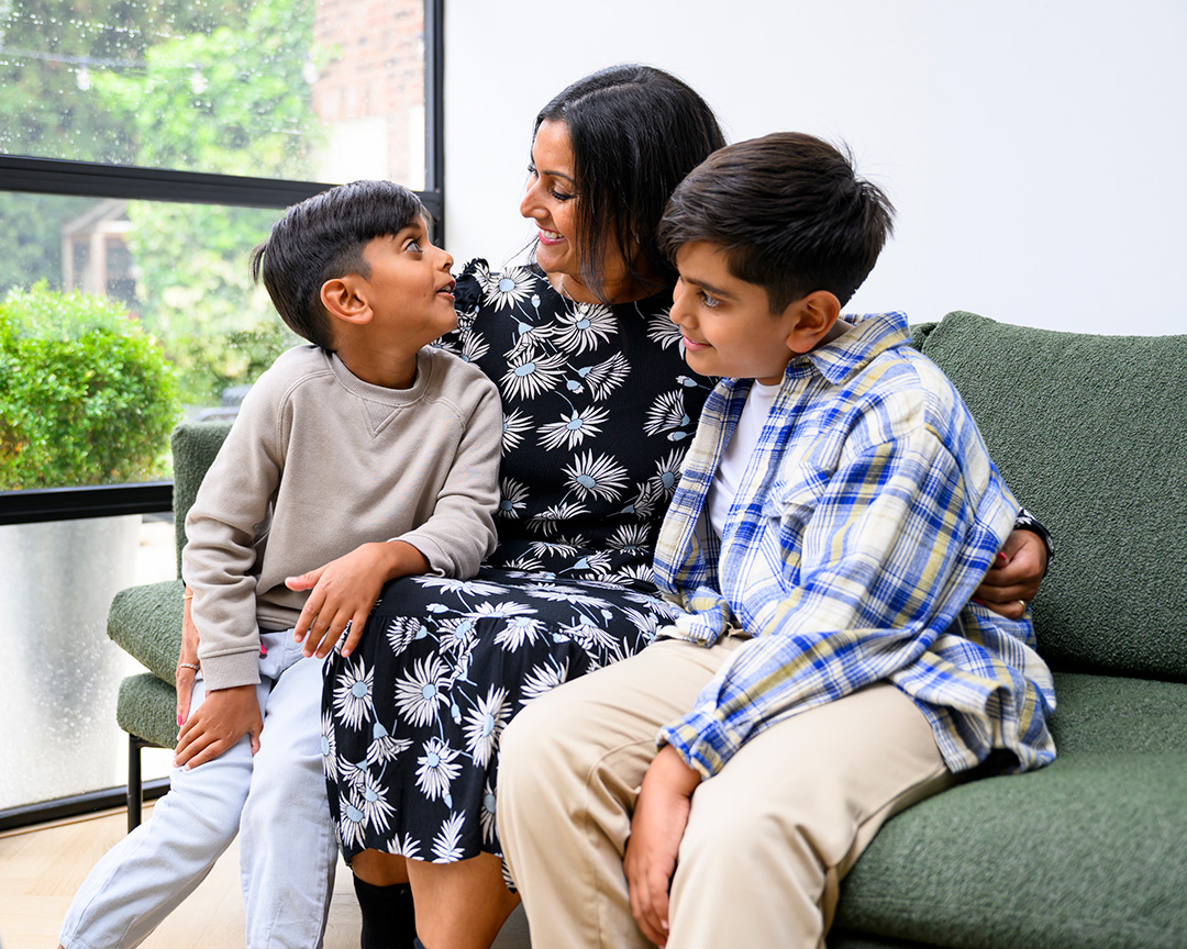 Mother sitting on couch with arms around two sons